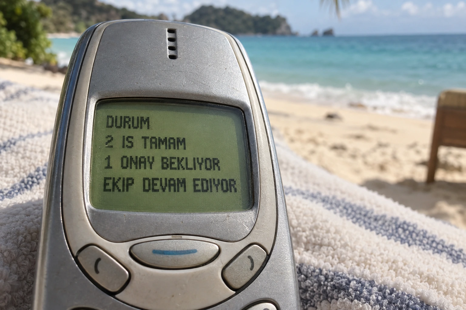 Sahildeki eski telefonun ekranında kurgusal durum mesajı: DURUM, 2 IS TAMAM, 1 ONAY BEKLIYOR, EKIP DEVAM EDIYOR.